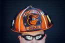 Wes Roberts, of Whiteford, Md., poses in a Baltimore Orioles-themed fireman's helmet before an opening day baseball game between the Orioles and the Boston Red Sox, Monday, March 31, 2014, in Baltimore. (AP Photo/Patrick Semansky)