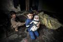 A Syrian refugee boy poses with his newborn brother as their mother lies near them in a house in the Basaksehir district of Istanbul, on March 4, 2014