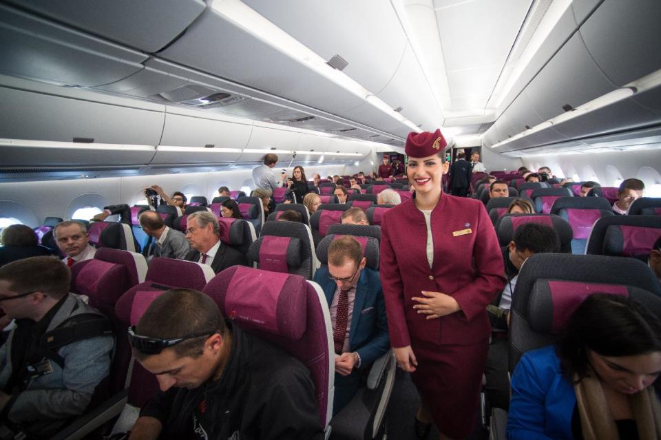 A Qatar Airways flight attendant smiles during  a flight  in an Airbus A350 over Toulouse, southwestern France, Monday, Dec.22, 2014.  After years of ...