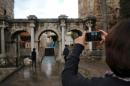 A tourist takes a picture of the Hadrian's Gate, a triumphal arch in the Mediterranean resort city of Antalya