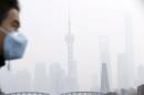 File photo of a man wearing a face mask walking on a bridge in front of the financial district of Pudong amid heavy smog in Shanghai