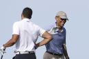 President Barack Obama, right, smiles as he gives a pat on the arm to Cyrus Walker, left, cousin of White House senior adviser Valerie Jarrett, while golfing at Vineyard Golf Club, in Edgartown, Mass., on the island of Martha's Vineyard, Tuesday, Aug. 12, 2014. President Obama is taking a two-week summer vacation on the island. (AP Photo/Steven Senne)