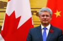 Canada's Prime Minister Harper stands in front of Chinese and Canadian national flags as he witnesses a signing ceremony at the Great Hall of the People in Beijing