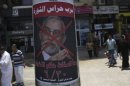 People walk past a defaced poster of Muslim Brotherhood leader Mohammed Badie near Tahrir Square in Cairo