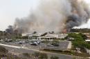 A wild fire burns toward a Aviara Oaks Middle School Wednesday, May 14, 2014, in Carlsbad, Calif. Wind-driven flames are threatening homes in the coastal city of Carlsbad, where officials have sent mandatory evacuation notices to more than 11,000 homes and businesses. (AP Photo)