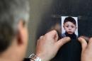 A man sticks a photo of missing Bosnian boy Mohamed on a wall at the State Office of Health and Social Affairs in Berlin on October 29, 2015