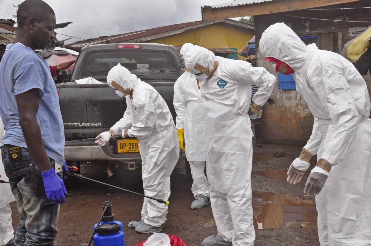 Health workers remove their protective clothes after carrying the body of a woman that they suspect died from the Ebola virus, in an area known as Clara Town in Monrovia, Liberia, Wednesday, Sept. 10, 2014. A surge in Ebola infections in Liberia is driving a spiraling outbreak in West Africa that is increasingly putting health workers at risk as they struggle to treat an overwhelming number of patients. A higher proportion of health workers has been infected in this outbreak than in any previous one. (AP Photo/Abbas Dulleh)