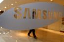 A man walks behind a logo of Samsung Electronics at the company's headquarters in Seoul