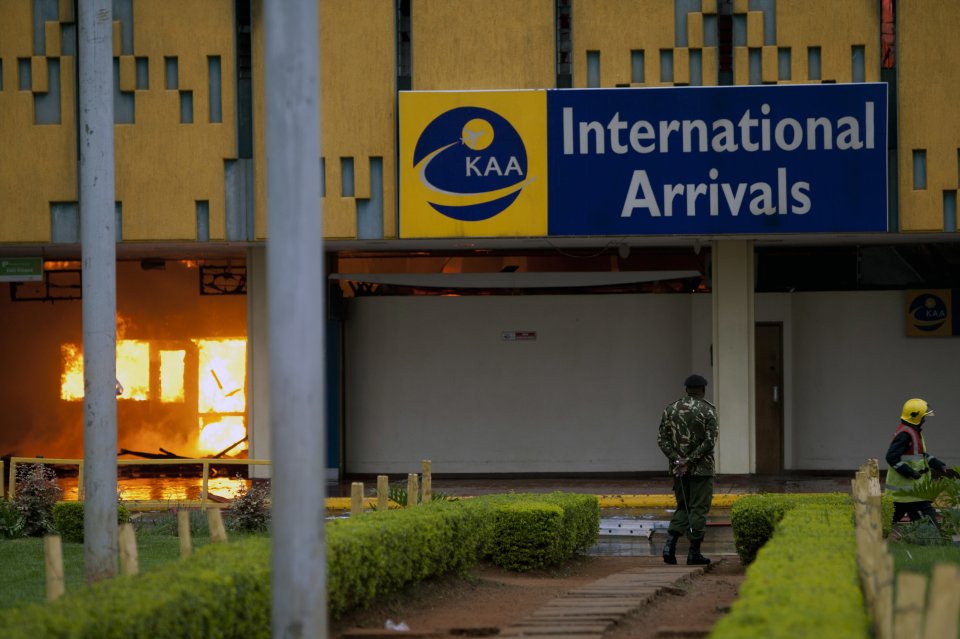 A policeman stands guard as a fire engulfs the arrivals hall of the Jomo Kenyatta International Airport in Nairobi, Kenya Wednesday, Aug. 7, 2013. The Kenya Airports Authority said the Kenya's main international airport has been closed until further notice so that emergency teams can battle the fire. (AP Photo/Sayyid Azim)