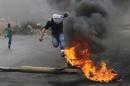 Palestinian protester jumps past a burning tyre during clashes with Israeli troops during clashes near the Jewish settlement of Bet El, near the West Bank city of Ramallah