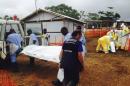 Volunteers carry bodies in a centre run by Medecins Sans Frontieres for Ebola patients in Kailahun