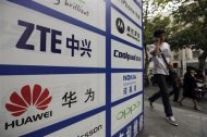 A man walks past an advertisement board showing the logos of Huawei and ZTE on it, outside a mobile phone repair shop in Wuhan October 11, 2012. REUTERS/Stringer