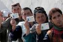 Afghan voters display their national identity cards as they queue to cast their votes at a polling station in Kandahar on April 5, 2014
