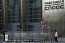 A woman walks past the entrance of the headquarters of China National Offshore Oil Corp in Beijing