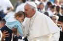 Pope Francis kisses a baby as he arrives to lead the weekly audience in Saint Peter's Square at the Vatican