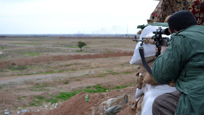 A Kurdish Peshmerga fighter keeps watch from a position in Tal al-Ward, 30 kms west of Kirkuk on December 14, 2014
