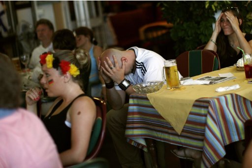 Germany soccer fans react after Italy's Balotelli scored his second goal against Germany as they watch their Euro 2012 semi-final on a tv at a restaurant in Fuengirola