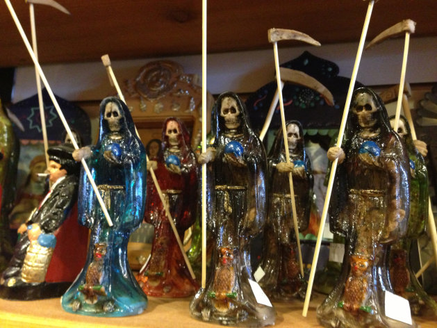 in this Feb. 13, 2013 photo, statues of La Santa Muerte are shown at the Masks y Mas art store in Albuquerque, N.M. La Santa Muerte, an underworld saint most recently associated with the violent drug trade in Mexico, now is spreading throughout the U.S. among a new group of followers ranging from immigrant small business owners to artists and gay activists. In addition to showing up at drug crime scenes, the once-underground icon has been spotted on passion candles in Richmond, Va. grocery stores. The folk saint's image can be seen inside New York City apartments, in Minneapolis religious shops and during art shows in Tucson, Ariz. (AP Photo/Russell Contreras)