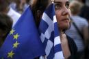 A pro-Euro protester holds a European Union and a Greek national flag during a rally in front of the parliament building in Athens