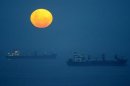 Ships lie at anchor outside the harbour at Durban, South Africa as a full moon rises on Boxing Day.