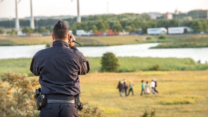 A French gendarme films migrants trying to enter the Eurotunnel in Coquelles near Calais, northern France, on July 31, 2015