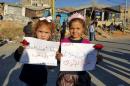Girls carry banners as they wait at Masnaa border crossing between Lebanon and Syria, for the arrival of their relatives, who are rebel fighters who left the town of Zabadani