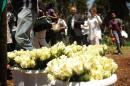 Relatives of victims of the Westgate Mall attack walk past roses at the memorial site on October 21, 2013 in Nairobi