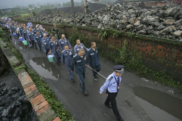 A policeman leads inmates …
