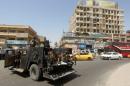 Members of Iraqi security forces monitor a street from an armoured vehicle outside Shorja market in central Baghdad on June 16, 2015