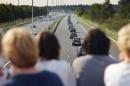 People watch a convoy of hearses bearing the remains of passengers and crew killed in the downing of Malaysia Airlines Flight 17 on July 17, as it makes its way along a highway near Boxtel, Netherlands, Thursday, July 24, 2014. The second flight of two military aircraft carrying remains of victims arrived in the Netherlands on Thursday. The bodies are to be taken to a military barracks in Hilversum, where a team of 25 forensic experts and dozens of support staff began working to identify remains Wednesday evening after coffins of the first flight arrived. (AP Photo/Phil Nijhuis)