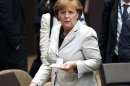 German Chancellor Angela Merkel carries a coffee to her seat at the 2012 NATO Summit in Chicago