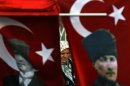 A woman wearing a traditional head-scarf is framed by Turkish flags depicting the founder of modern Turkey, Mustafa Kemal Ataturk, in Istanbul's Taksim square