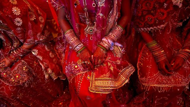 FILE - In this Feb. 20, 2015 file photo, Indian brides from impoverished families, dressed in wedding finery, wait for their grooms to arrive during a mass marriage ceremony in New Delhi, India when 12 couples tied the knot in a single ceremony organized by a social organization, that would otherwise have cost each family thousands of dollars. An Indian bride has walked out of her wedding ceremony after her groom-to-be failed to solve a simple math problem, police said Friday, March 13, 2015. The question she asked: How much is 15 plus six? His reply: 17. The incident took place late Wednesday, March 11 in Rasoolabad village near the industrial town of Kanpur in northern Uttar Pradesh state. [AP Photo/Saurabh Das, File)