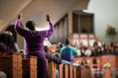 A woman raises her hands as the choir sings before U.S. Attorney General Eric Holder speaks to members of the community during an interfaith service at Ebenezer Baptist Church, the church where The Rev. Martin Luther King Jr. preached, Monday, Dec. 1, 2014, in Atlanta. Holder traveled to Atlanta to meet with law enforcement and community leaders for the first in a series of regional meetings around the country. The president asked Holder to set up the meetings in the wake of clashes between protesters and police in Ferguson, Missouri. (AP Photo/David Goldman)