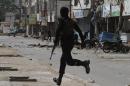A Pakistani police commando rushes to the site of an explosion in Karachi, Pakistan, Wednesday, May 21, 2014. A bomb rigged to a motorcycle exploded outside an office belonging to the Pakistani paramilitary forces in the southern city of Karachi, wounding seven civilian, said police official Javed Odho. (AP Photo/Fareed Khan)