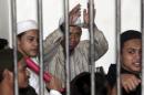 File picture shows radical Muslim cleric Aman Abdurrahman, also known as Oman Rochman, raising his hands in a holding cell as he waits with other militants for their trial in Jakarta