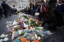 People gather in front of flowers that were laid outside the French embassy in Rome, Saturday, Nov. 14, 2015. French police on Saturday hunted possible accomplices of eight assailants who terrorized Paris concert-goers, cafe diners and soccer fans with a coordinated string of suicide bombings and shootings in France's deadliest peacetime attacks. (AP Photo/Gregorio Borgia)
