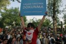 A woman holds up a banner that reads "Don't interfere with my life style " as thousands of people gather in support of demonstrators staging a sit-in to prevent the uprooting of trees at an Istanbul park, in Ankara, Turkey, Friday, May 31, 2013. Riot police clash with demonstrators after they used tear gas and pressurized water in a dawn raid on Friday to rout a peaceful demonstration by thousands of people in Istanbul. Several protesters were injured when a wall they climbed collapsed during a police chase. Police moved in to disperse the crowd on the fourth day of the protest against a government plan to revamp Istanbul's main square, Taksim. (AP Photo/Burhan Ozbilici)