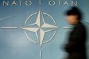 A WOMAN WALKS PAST THE NATO LOGO IN BRUSSELS.