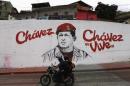 A motorcycle rides past a mural depicting late Venezuelan President Hugo Chavez, near his mausoleum in Caracas