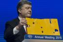 Ukrainian President Petro Poroshenko shows a piece of a bus that was attacked recently during the panel "The Future of Ukraine" in Davos, Switzerland, Wednesday, Jan. 21, 2015. The meeting runs Jan. 21 through 24 under the overarching theme "The New Global Context". (AP Photo/Michel Euler)