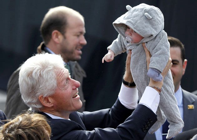 الرئيس الأمريكي السابق بيل كلينتون يدلل طفل قابله خلال أحد لقاءاته السياسية