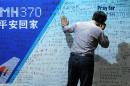 A man looks at a billboard in commemoration of flight MH370 at the Metro Park Lido Hotel in Beijing on March 30, 2014