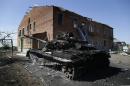 A burned Ukrainian army tank is seen near a destroyed kindergarten in the village of Kominternove, Ukraine, Saturday, Sept. 6, 2014. After four months of war, eastern Ukraine begins the first full day of an uncertain cease-fire. The truce agreement calls for an exchange of prisoners and establishment of humanitarian corridors, but how quickly those actions will begin is unclear. (AP Photo/Sergei Grits)