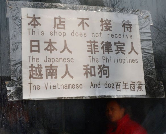 A Chinese cook works in a restaurant behind a sign reading: "This shop does not receive the Japanese, The Philippines, The Vietnamese and Dog" in the historic tourist district of Houhai in Beijing on February 26, 2013. Photographs of the controversial sign have gone viral in Vietnamese-language forums and featured heavily in Philippine newspapers and websites