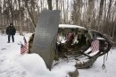 In this photo made Friday, Dec. 14, 2012, Greenville, Maine, Police Chief Jeff Pomerleau views a monument next to wreckage from a B-52 bomber on Elephant Mountain near Greenville, Maine. The plane's 40-foot-tall vertical stabilizer had snapped off and crashed on Jan. 24, 1963. Seven of the nine people on board died in the crash. (AP Photo/Robert F. Bukaty)