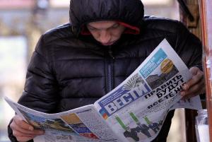 A man reads a newspaper bearing headlines on the results &hellip;