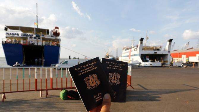 A Syrian man holds Syrian passports as he waits to board a passenger ferry heading to Turkey at Lebanon's northern port city of Tripoli on October 6, 2015