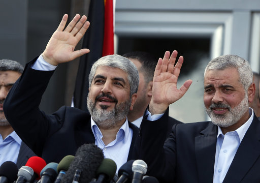 Exiled Hamas chief Khaled Mashaal, left, and Gaza's Hamas Prime Minister Ismail Haniyeh wave during a news conference upon Meshaal's arrival at Rafah crossing in the southern Gaza Strip, Friday, Dec. 7, 2012. Mashaal broke into tears Friday as he arrived in the Gaza Strip for his first-ever visit, a landmark trip reflecting his militant group's growing international acceptance and its defiance of Israel. Khaled Mashaal, who left the West Bank as a child and leads the Islamic militant movement from Qatar, crossed the Egyptian border, kissed the ground, and was greeted by a crowd of Hamas officials and representatives of Hamas' rival Fatah party. He was also welcomed by a group of Palestinian orphans — children of Gaza militants killed by Israel in recent years — wearing military-style uniforms. (AP Photo/Suhaib Salem, Pool)