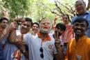 A supporter of India's main opposition Bharatiya Janata Party (BJP) wears a mask of party leader and India's next prime minister Narendra Modi as he celebrates with others preliminary results that show the BJP winning by a landslide, in Bangalore, India, Friday, May 16, 2014. The BJP now has a decisive lead for 272 seats in the lower house of Parliament, the majority needed to create an independent government without forming a coalition with smaller parties. The full results are expected later in the day but it's unlikely that Modi's party would see a significant reversal. (AP Photo/Aijaz Rahi)